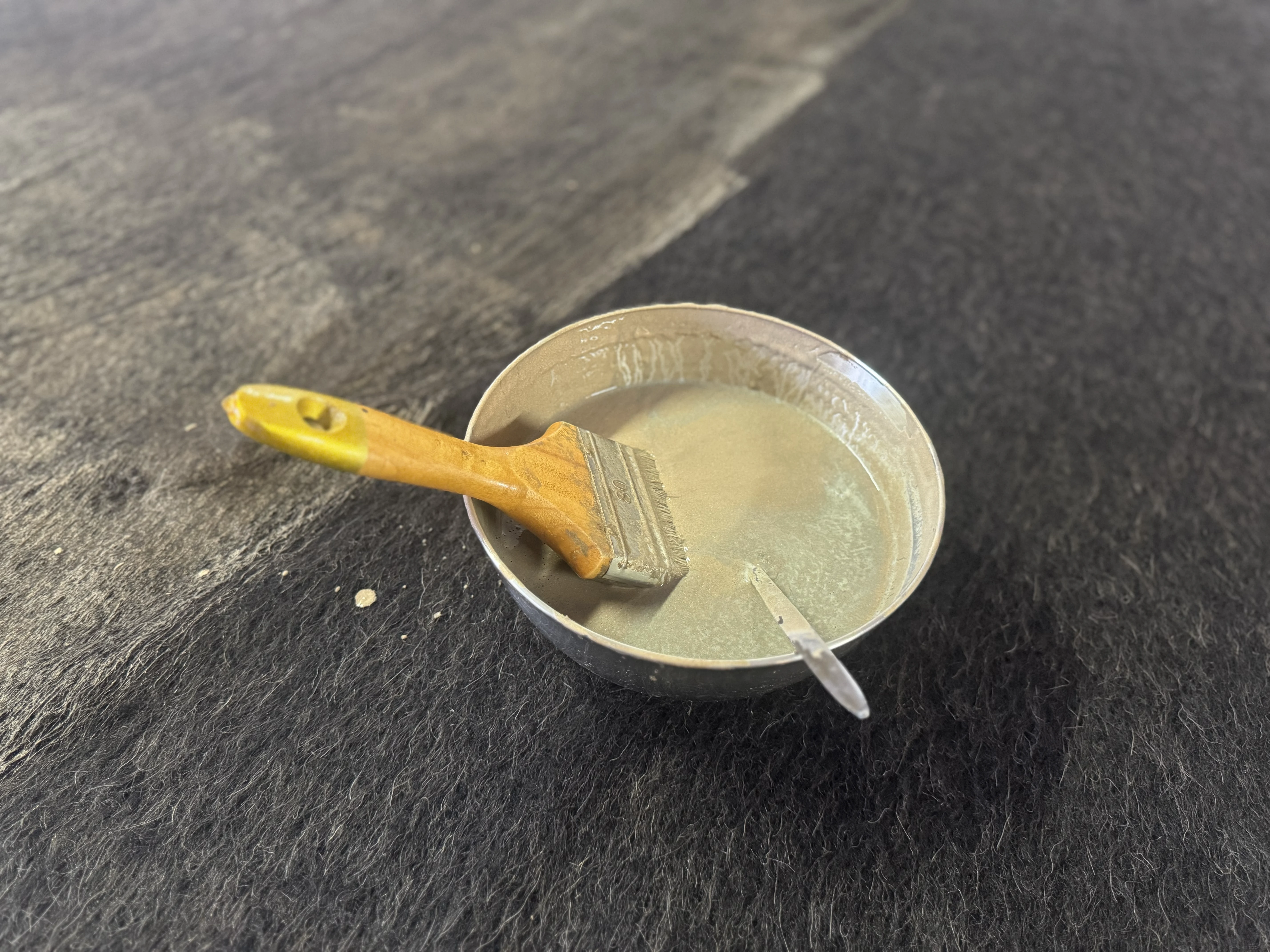 Pinsel und Schale mit goldfarbenem Finish auf dunklem RUNDHOLZ-Stoff