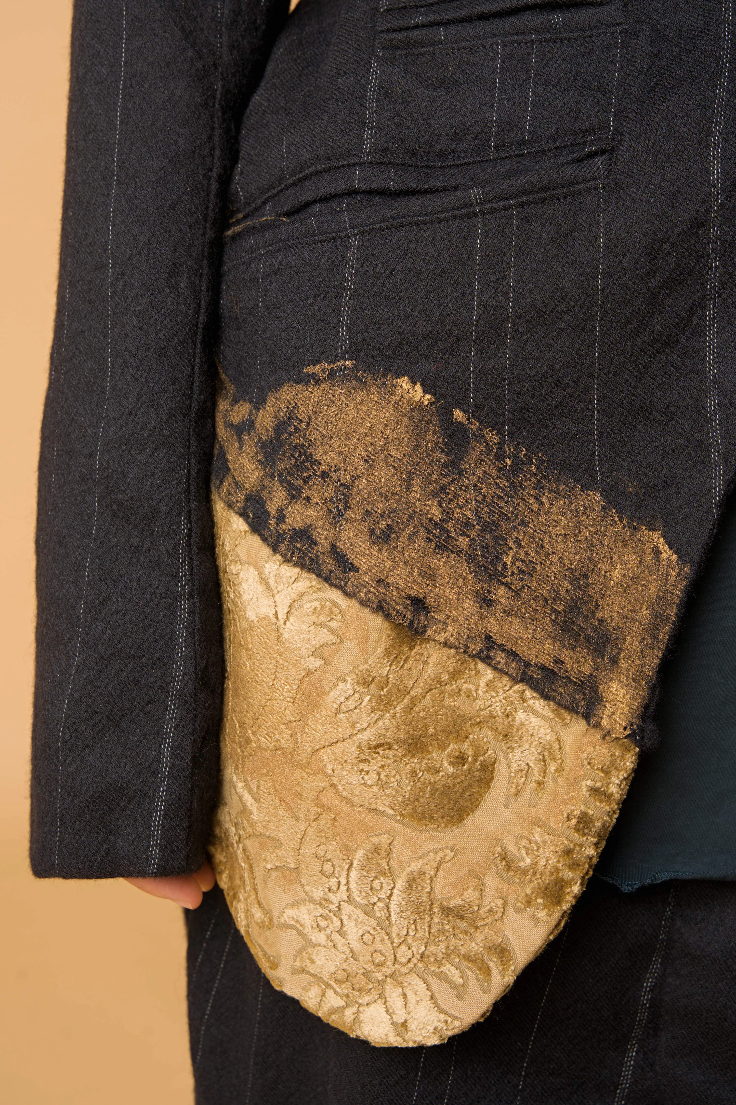 Detail des von Hand aufgebrachten goldfarbenen Finishs der Nadelstreifenjacke